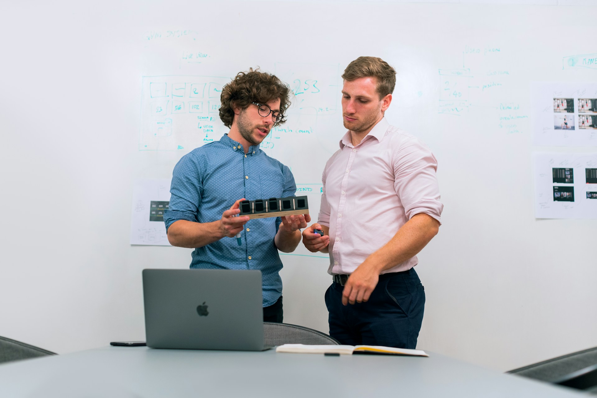 a tech founder and his cofounder standing in front of a whiteboard